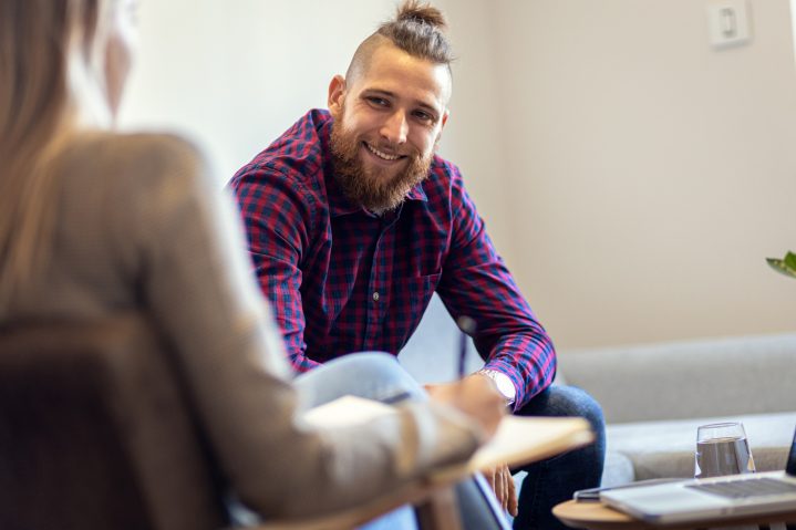 Young man talking to female psychologist during session.